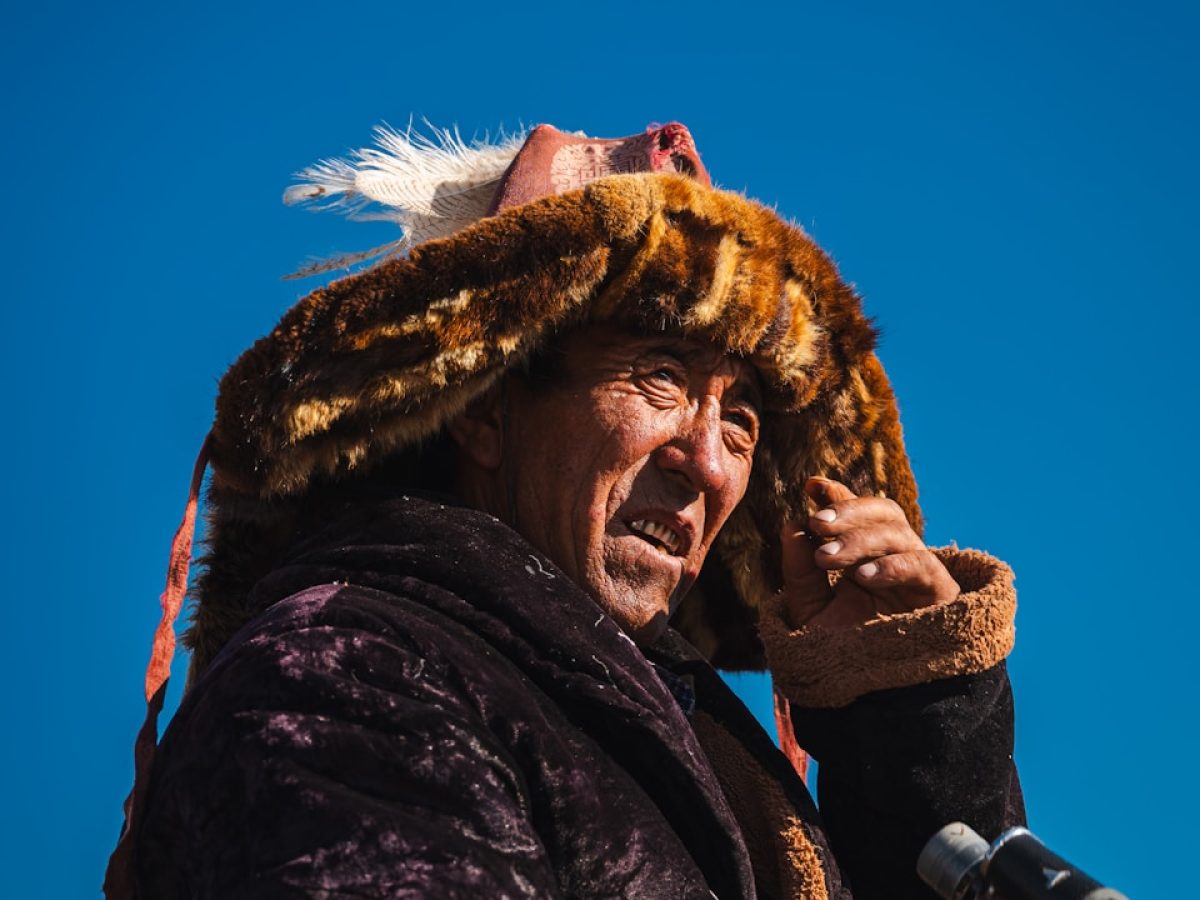 Mongolian man wearing a fur hat and holding binoculars. resham firiri