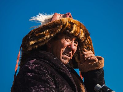 Mongolian man wearing a fur hat and holding binoculars. resham firiri
