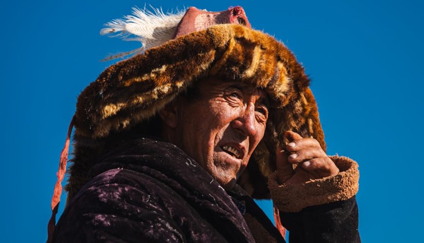 Mongolian man wearing a fur hat and holding binoculars. resham firiri