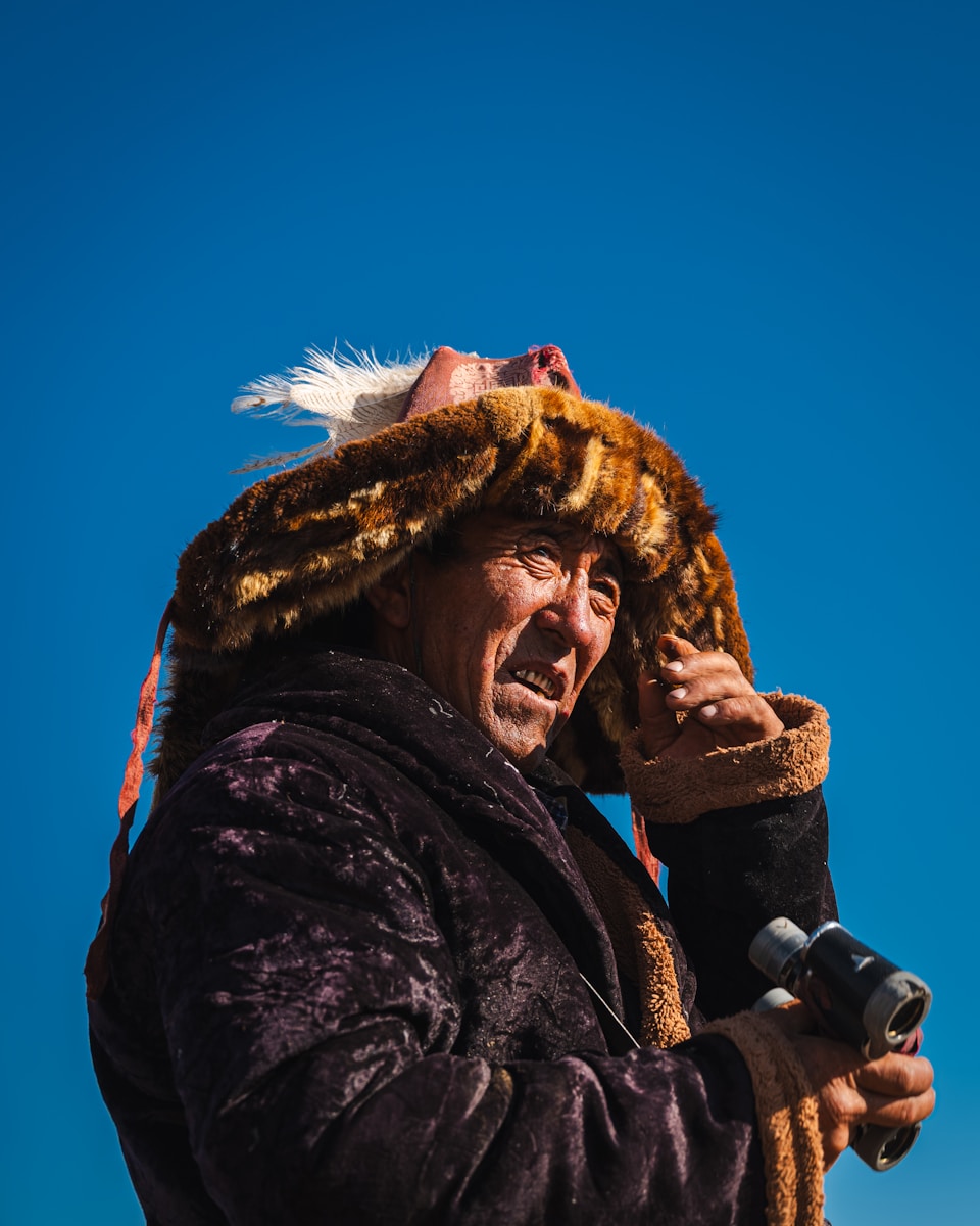 Mongolian man wearing a fur hat and holding binoculars. resham firiri